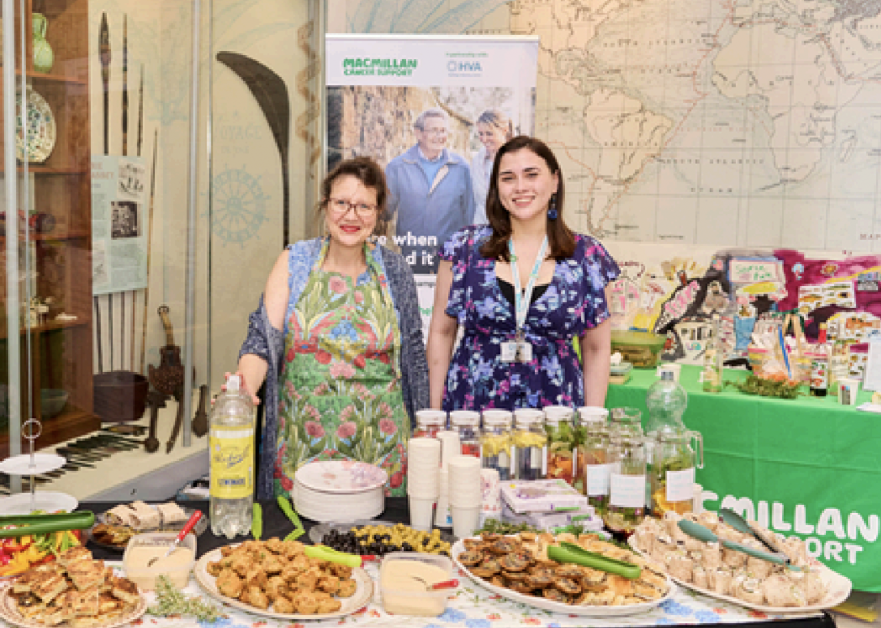 Two members of the HVA team at a Cancer Champions event with food at the table