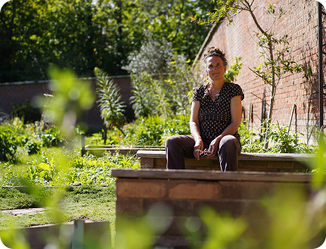 A women sits in a community garden looking peaceful