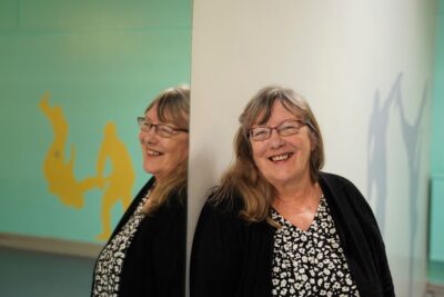 A woman smiling leaning against a wall