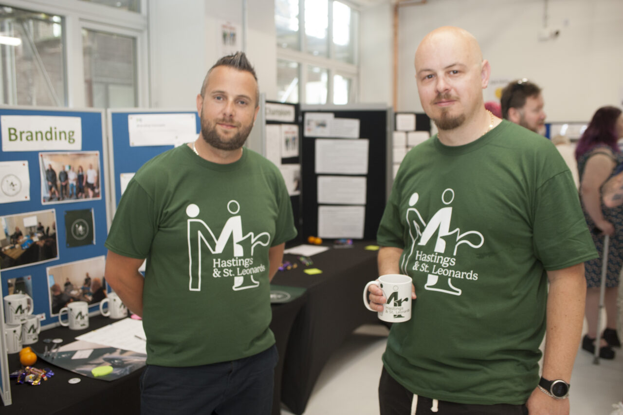 Two men having a cup of tea at their exhibition stand for Mr Hastings & St Leonards