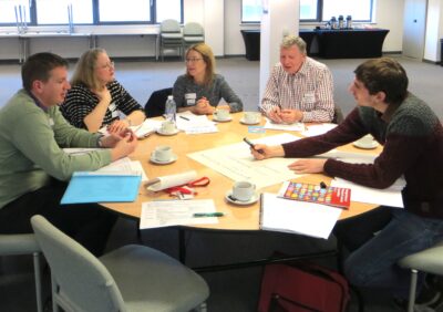 Meeting at a round table with lots of pens and flip chart paper