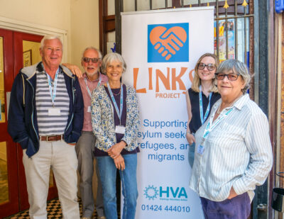 A groups of people stood smiling in front of the Links Project banner