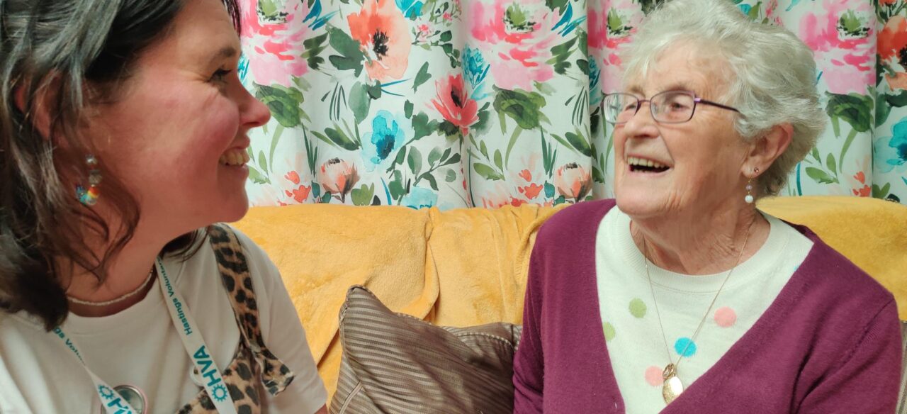 A member of HVA staff with a member of the community sat on a sofa