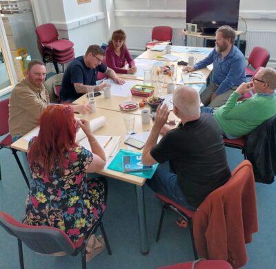 People participate in activities around a table at a men's health workshop