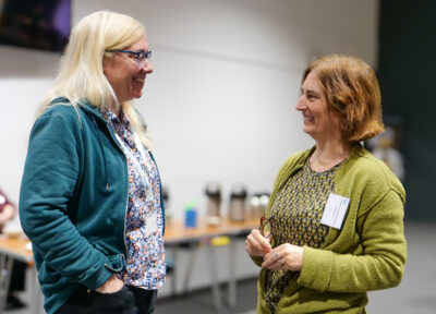 Two people chat together at a HVA event, smiling at one another